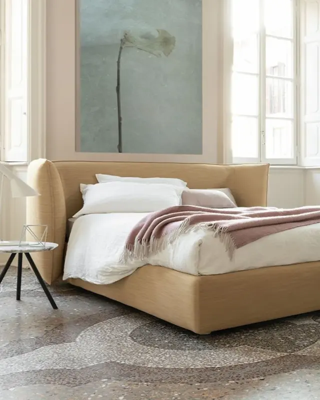 Cama Jill de Bolzan con cabecero tapizado envolvente y líneas suaves, ideal para crear ambientes íntimos y confortables.