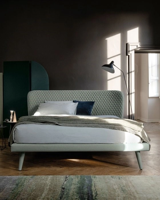 Cama Corolle de Bolzan con cabecero tapizado en rombos y diseño elegante adaptable a distintos estilos.